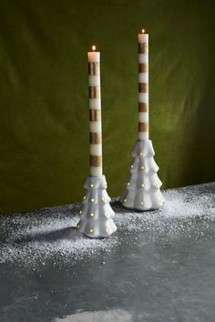 two tall candles are decorated with white and gold lights in the shape of christmas trees