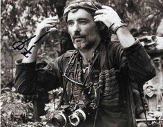 a black and white photo of a man holding a camera in front of his head