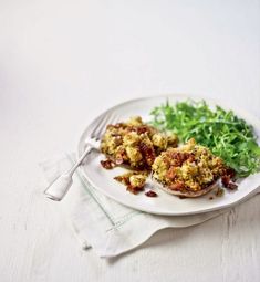 a white plate topped with eggs covered in crumbs next to a green leafy salad