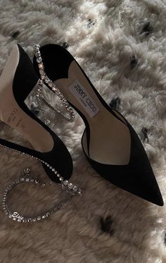 two pairs of black high heeled shoes sitting on top of a fur covered floor