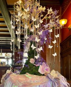 a table topped with a purple and white centerpiece covered in flowers, chains and butterflies