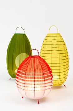 three different colored paper lanterns sitting next to each other on top of a white surface