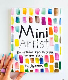 a person holding up a book that says mini artist