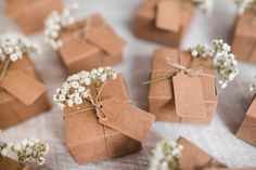 small brown boxes with tags tied to them and baby's breath flowers on the table