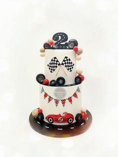 a three tiered cake decorated with racing cars and numbers on the top, sitting on a plate