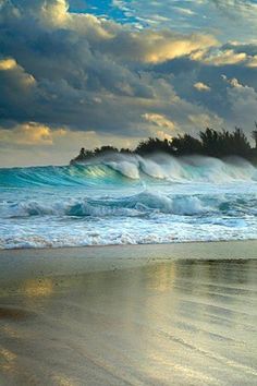 an ocean beach with waves crashing on the shore and clouds in the sky above it