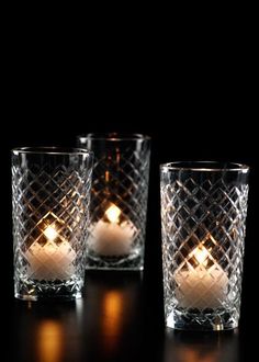 three glasses with candles in them sitting on a table