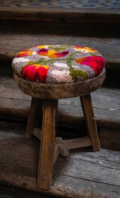 an old wooden stool with flowers painted on the seat is sitting in front of some steps