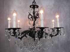 a chandelier with five lights hanging from it's sides and three candles on each side