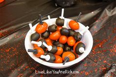 a bowl filled with lots of orange and black candies on top of a table