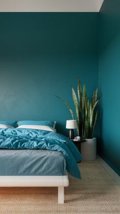 a bed sitting in a bedroom next to a green wall and a potted plant