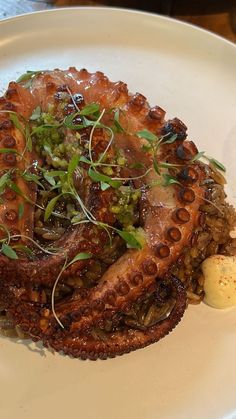 an octopus dish on a white plate with some garnish and a boiled egg