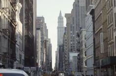 a city street filled with tall buildings and cars driving down the road next to each other