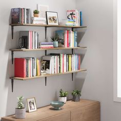 a shelf with books and plants on it in a room next to a wall mounted clock