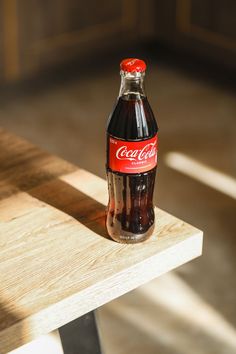 a coca cola bottle sitting on top of a wooden table