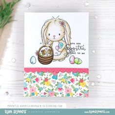 a card with a bunny holding an egg and some flowers on the table next to it