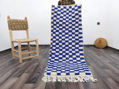 a blue and white blanket sitting on top of a wooden floor next to a chair