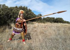 a man dressed in armor holding a wooden stick