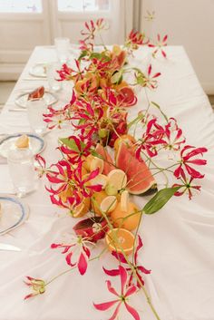 a long table with flowers and plates on it