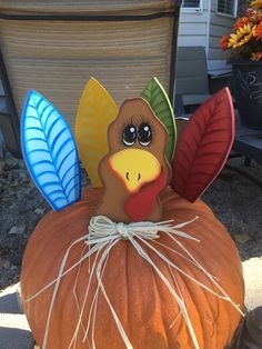 a fake turkey sitting on top of a pumpkin with leaves around it's head