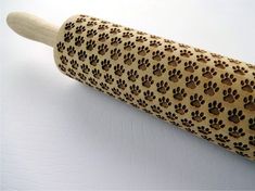 a wooden rolling pin with dog paw prints on the outside and inside, sitting on a white surface