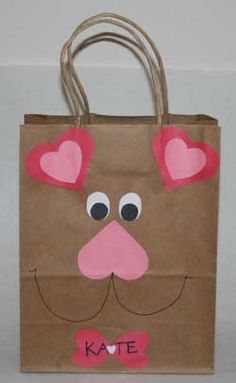 a brown paper bag with pink ears and hearts on its nose is sitting on a table