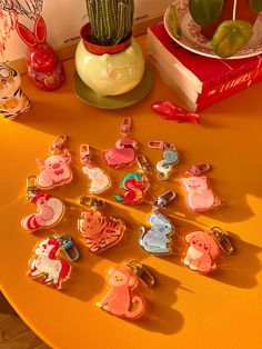 a table topped with lots of different shaped keychains next to a potted plant