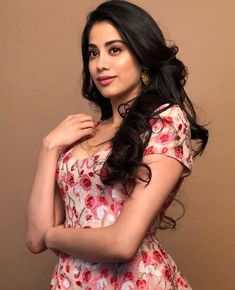 a woman in a floral dress posing for the camera with her hand on her shoulder