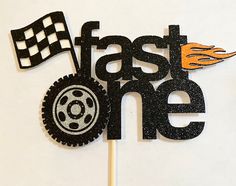 a cake topper with the words fast one on it and a race car flag