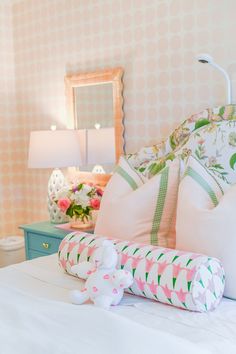 a white bed topped with lots of pillows next to a night stand and table lamp