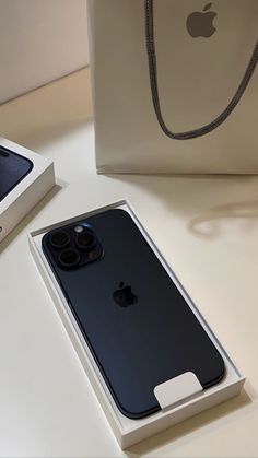 an apple phone is sitting in its box next to a white bag on the table