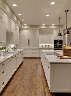 a large kitchen with white cabinets and wood floors