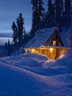 a cabin is lit up in the snow at night