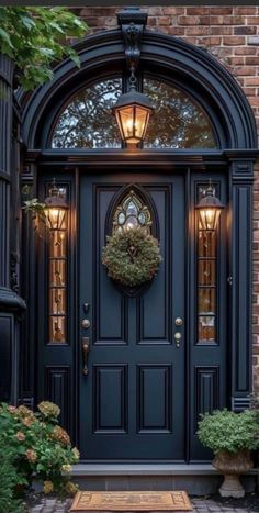 a blue front door with a wreath on the top and two lights above it, surrounded by greenery