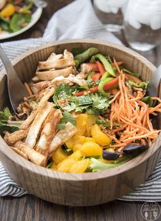 a wooden bowl filled with lots of different types of food on top of a table