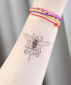 a woman's arm with a bee tattoo on the wrist and colorful bracelets