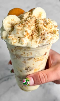 a hand holding an ice cream sundae with banana slices and cinnamon sprinkles