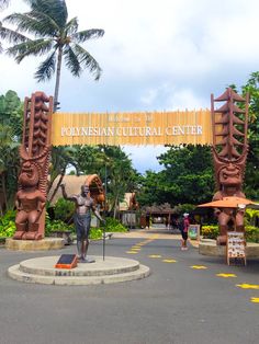 an entrance to a cultural center with statues and palm trees