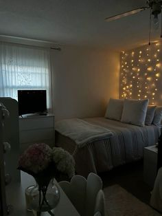 a bed room with a neatly made bed and lights on the wall