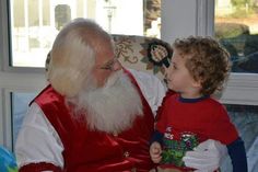 a little boy sitting next to santa clause