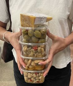 a person holding three plastic containers filled with food