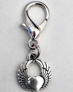 a silver charm with an angel heart and wings on it's end, sitting on a white surface