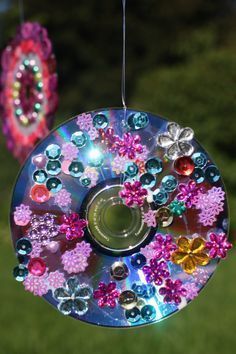 a colorful wind catcher hanging from a string with beads and flowers on it's side