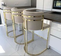 four stools in the middle of a kitchen with white countertops and cabinets behind them