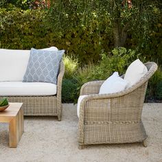 two wicker chairs sitting next to each other on top of a cement floor covered patio