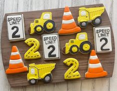 decorated cookies in the shape of trucks and road signs on a wooden board with traffic cones