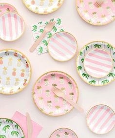 pink and white plates with pineapples on them are laid out in the shape of palm trees