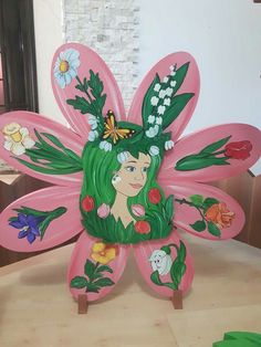 a pink butterfly with green hair and flowers on it's wings, sitting on a table