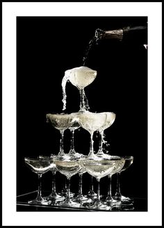 champagne being poured into wine glasses in front of a black background