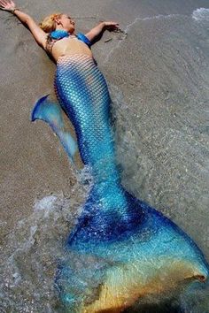 a woman laying on top of a blue and yellow mermaid tail